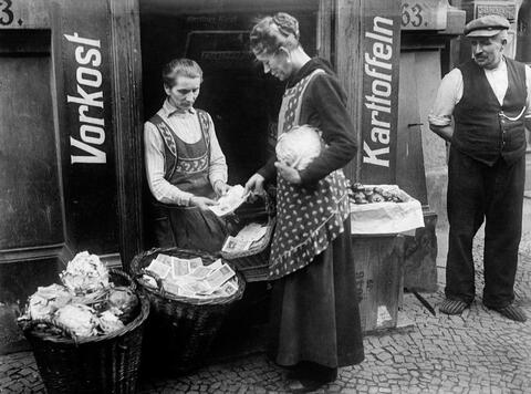 A woman takes a basket of banknotes to buy cabbage at a market during the 1933 hyperinflation in Weimar Germany.