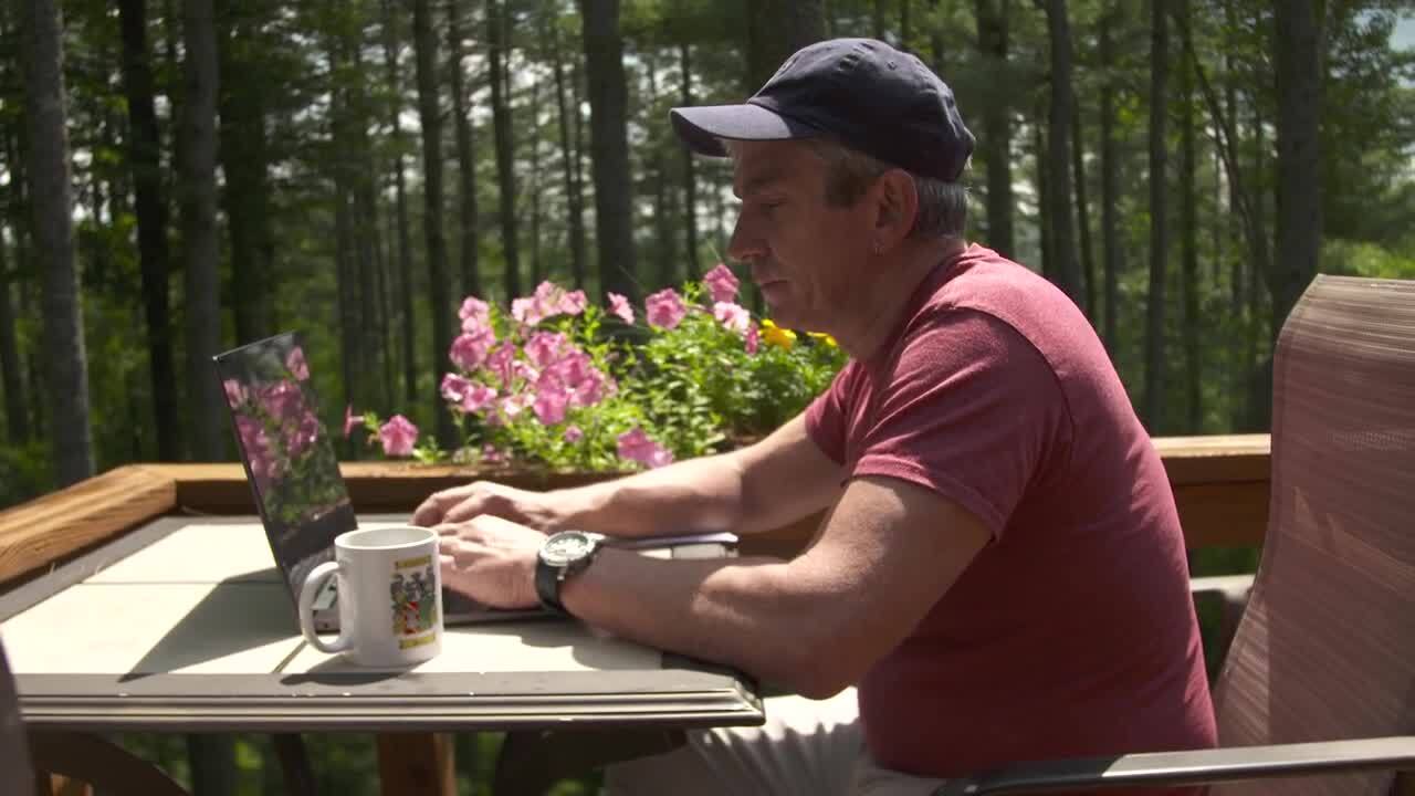 Man sitting outside and typing on a laptop.