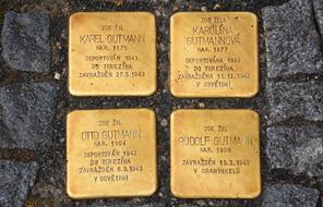 Four golden squares with inscriptions are built into the sidewalk.
