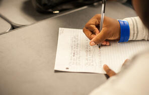 A close up of a student writing on a piece of paper.