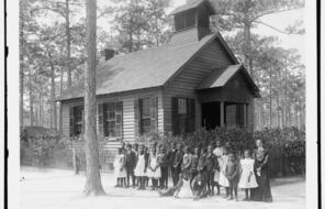 Black students standing outside in front of a clapboard school house