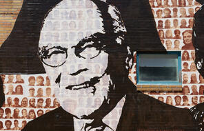 A black and white painting of Dr. Sheldon Korones on the Memphis Upstanders Mural, a painting on a brick wall in Memphis, TN.