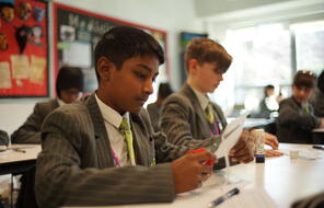 A student cuts a sheet of paper in a classroom at Skinners' Academy in Londonn