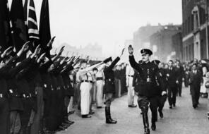 Oswald Mosley saluting a group of soldiers as he walks by