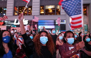 Masked crowd holding American flags. 