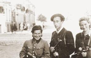 Three Jewish partisans (Vitka Kempner,  Abba Kovner, and Rozka Korczak) stand in the street during World War II.