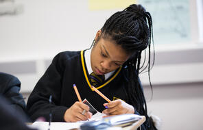 Photograph of student in uniform working on a worksheet in class