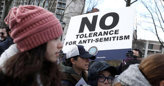Protestor holding "No Tolerance for Anti-Semitism" sign at demonstration