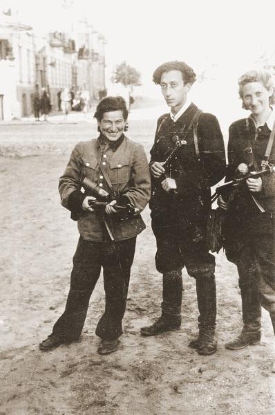 Three Jewish partisans (Vitka Kempner,  Abba Kovner, and Rozka Korczak) stand in the street during World War II.