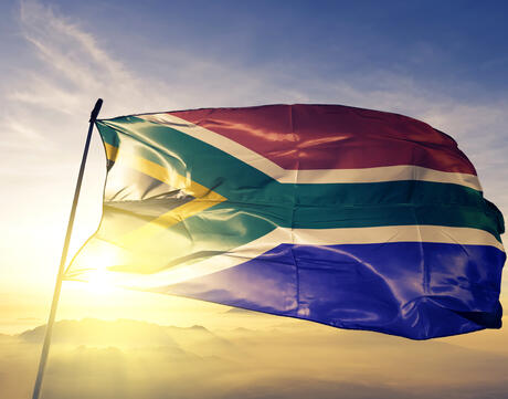South Africa flag waving during the sunrise with mist fog.