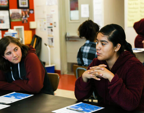 A student speaks while another listens attentively.