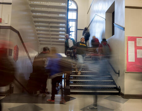 Photograph of students moving through a stairwell between classes.